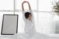 Asian woman Beautiful young smiling woman sitting on bed and stretching in the morning at bedroom after waking up in her bed full Royalty Free Stock Photo