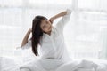 Asian woman Beautiful young smiling woman sitting on bed and stretching in the morning at bedroom after waking up in her bed full Royalty Free Stock Photo