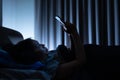 Asian woman on bed late at night and using mobile smartphone Royalty Free Stock Photo