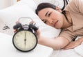 Asian woman on bed reaching out to stop alarm clock Royalty Free Stock Photo