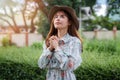 Asian woman believe in the prayer to God. Pretty girl make a wish motion on blurred park background