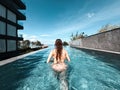 Asian woman in bikini in infinity swimming pool edge. luxury vacation near the sea. Royalty Free Stock Photo