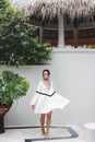 Asian woman in white light tunic, barefoot. Casual style, tropical garden. Royalty Free Stock Photo