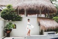 Asian woman in white light tunic, barefoot. Casual style, tropical garden. Royalty Free Stock Photo