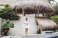 Asian woman in white light tunic, barefoot. Casual style, tropical garden. Royalty Free Stock Photo