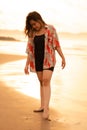 An Asian woman with blonde hair and a red shirt walks along the beach to enjoy the sea view Royalty Free Stock Photo