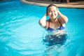 Asian woman in a blue bikini swims in the pool