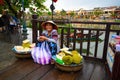 Asian fruit seller woman with traditional baskets in tourist destination Hoi An. Vietnamese vendor women in Hoi An, Vietnam