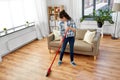 Asian woman with broom sweeping floor and cleaning