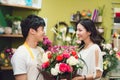 Asian woman buying a bouquet of fresh flowers and smiling at the store assistant in a flower shop