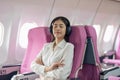 Asian woman in cabin wearing headphone resting while listening to music in airplane during flight Royalty Free Stock Photo