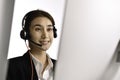 Asian woman call centre working use headset look at computer screen. Portrait of smiling Asian female customer service Royalty Free Stock Photo