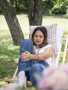 Asian woman on canvas chair in garden using mobile smart phone. female playing social network on internet. Royalty Free Stock Photo