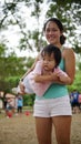 Asian woman carrying toddler and participating in family games