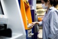 Asian woman at the cash machine withdraw money,girl is using tissue paper to press the ATM keyboard instead of the finger,avoid Royalty Free Stock Photo
