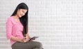 Asian woman in casual cloth holding credit card and using to online shopping with tablet at white brick wall.Digital technology l Royalty Free Stock Photo