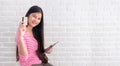 Asian woman in casual cloth holding credit card and using to online shopping with tablet at white brick wall.Digital technology l Royalty Free Stock Photo