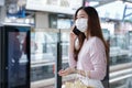 Asian woman in casual clothes wearing face mask talking on mobile phone while waiting for the train to go to work Royalty Free Stock Photo