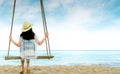 Asian woman in casual style wear hat and sandals sit on swings at sand beach and looking beautiful tropical paradise sea and sky. Royalty Free Stock Photo