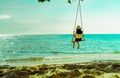 Asian woman in casual style wear hat swing the swings at sand beach and looking beautiful tropical paradise sea and sky on sunset Royalty Free Stock Photo