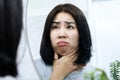 Asian woman checking her double chin under her lower jaw in front of a mirror, a sign of weight gain or obesity Royalty Free Stock Photo