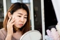 Asian woman checking her face skin problem with acne scar, dark spot on mirror
