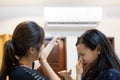 Asian woman and child girl are closing her nose, bad smell,musty smell of air conditioner has a problems,dust and dirt coming in