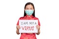 Asian woman in Chinese costume wear a hygienic mask holding sign I am not a VIRUS for anti racism , bullying and hate