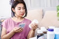 Asian woman choosing dietary supplements hand holding mobile phone and reading instruction