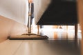 Asian woman cleaning and mopping the floor under the sofa with a microfiber wet mop pad in the living room. Royalty Free Stock Photo