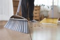 Asian woman cleaning and sweeping dust the floor with a broom in the living room. Woman doing chores at home. Royalty Free Stock Photo