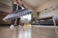 Asian woman cleaning and sweeping dust the floor with a broom in the living room. Woman doing chores at home. Royalty Free Stock Photo