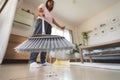 Asian woman cleaning and sweeping dust the floor with a broom in the living room. Woman doing chores at home. Royalty Free Stock Photo