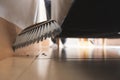 Asian woman cleaning and sweeping dust the floor under the sofa with a broom in the living room. Royalty Free Stock Photo