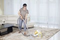 Asian woman cleans carpet with a vacuum cleaner Royalty Free Stock Photo