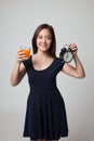 Asian woman with a clock drink orange juice.
