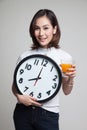 Asian woman with a clock drink orange juice.