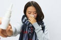 Asian woman with a cold with a stuffy nose holding a nasal spray for allergies with a sore throat wearing a checkered Royalty Free Stock Photo