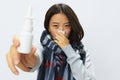 Asian woman with a cold with a stuffy nose holding a nasal spray for allergies with a sore throat wearing a checkered Royalty Free Stock Photo