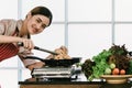 Asian woman cook are frying salmon in a frying pan in a modern kitchen