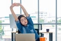 Asian woman creative designer stretching arms up from working with laptop in modern office.take a break from work Royalty Free Stock Photo