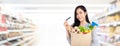 Asian woman with credit card holding paper bag full of groceries Royalty Free Stock Photo