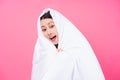 Asian woman curled up in blankets on pink background Royalty Free Stock Photo
