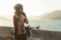 Asian woman cyclist wearing a helmet getting ready for a bike ride around the lake in the morning with beautiful mountain view in