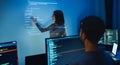 asian woman developers collaborating on a coding project, with one member pointing at code projected on the wall while the other Royalty Free Stock Photo
