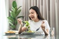 Asian woman dip fresh vegetable salad with a fork to eating healthy meal on the table in dining room at home Royalty Free Stock Photo