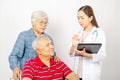 Asian woman Doctor talking to senior couple in wheelchair at hospital. Beautiful asian doctor taking care of patient in wheelchair Royalty Free Stock Photo