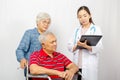 Asian woman Doctor talking to senior couple in wheelchair at hospital. Beautiful asian doctor taking care of patient in wheelchair Royalty Free Stock Photo