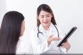 Asian woman doctor who wears medical uniform gives information and suggestion to woman patient in healthcare concept Royalty Free Stock Photo