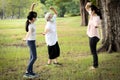 Asian woman is doing exercise activity for the old elderly and child girl,family workout,wearing protective mask outdoor at park,